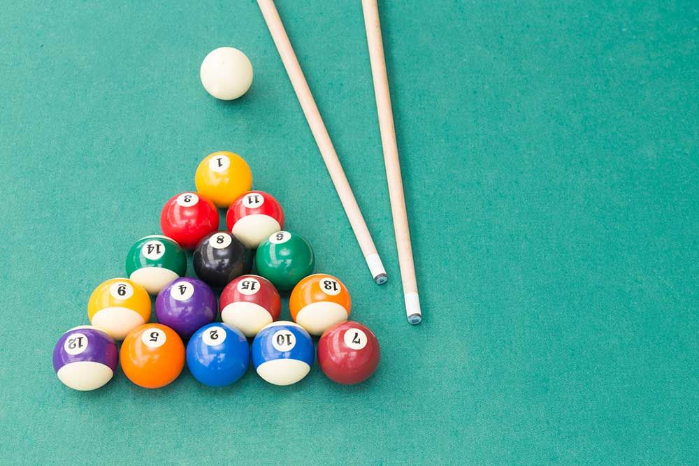 Pool balls racked on blue cloth with two cues