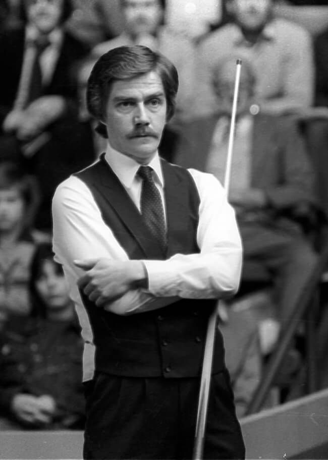 Cliff Thorburn in waistcoat and tie, arms folded, cue in hand